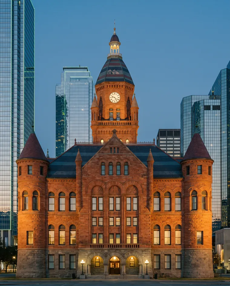 Old Red, the red sandstone 1892 Dallas County Courthouse, at dusk with downtown towers behind